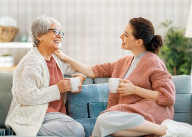 Güzel anne ve kız evdeki kanepede otururken konuşuyor ve gülümsüyor..