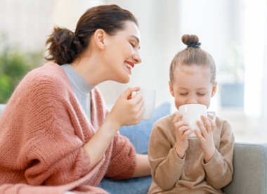 Anne ve kızı oynuyorlar, gülümsüyorlar ve evde çay içiyorlar.. 