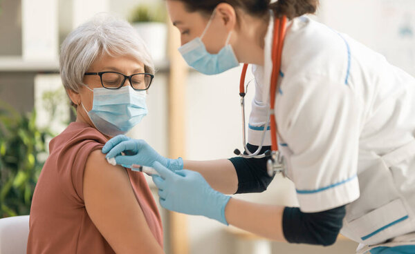 Doctor giving a senior woman vaccination. Virus protection. COVID-2019.