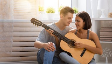 Aşık mutlu bir çift. Genç şık moda çiftimizin göz kamaştırıcı şehvetli portresi. Genç adam sevgili kızı için gitar çalıyor..