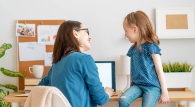 Bilgisayarda çalışan çocuklu genç bir anne. Aile evde. Uzak çalışma. 