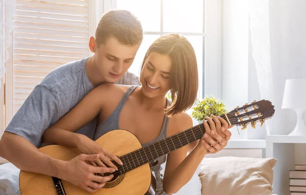 恋爱中的快乐夫妻 令人惊奇的性感画像年轻时尚夫妇在室内 年轻人为他心爱的女孩弹奏吉他 — 图库照片