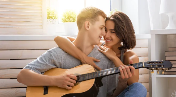 愛の幸せなカップル 室内で若いスタイリッシュなファッションカップルの見事な官能的な肖像画 若いです男遊びギターのために彼の最愛の女の子 — ストック写真