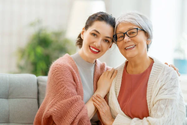 漂亮的母亲和女儿坐在沙发上谈笑风生 — 图库照片