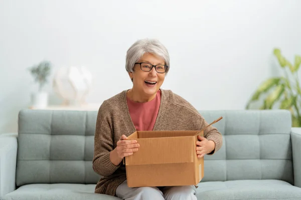 Mooie Senior Vrouw Houdt Kartonnen Doos Zittend Bank Thuis — Stockfoto