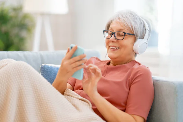 Femme Âgée Écoutant Musique Dans Les Écouteurs Assis Sur Canapé — Photo