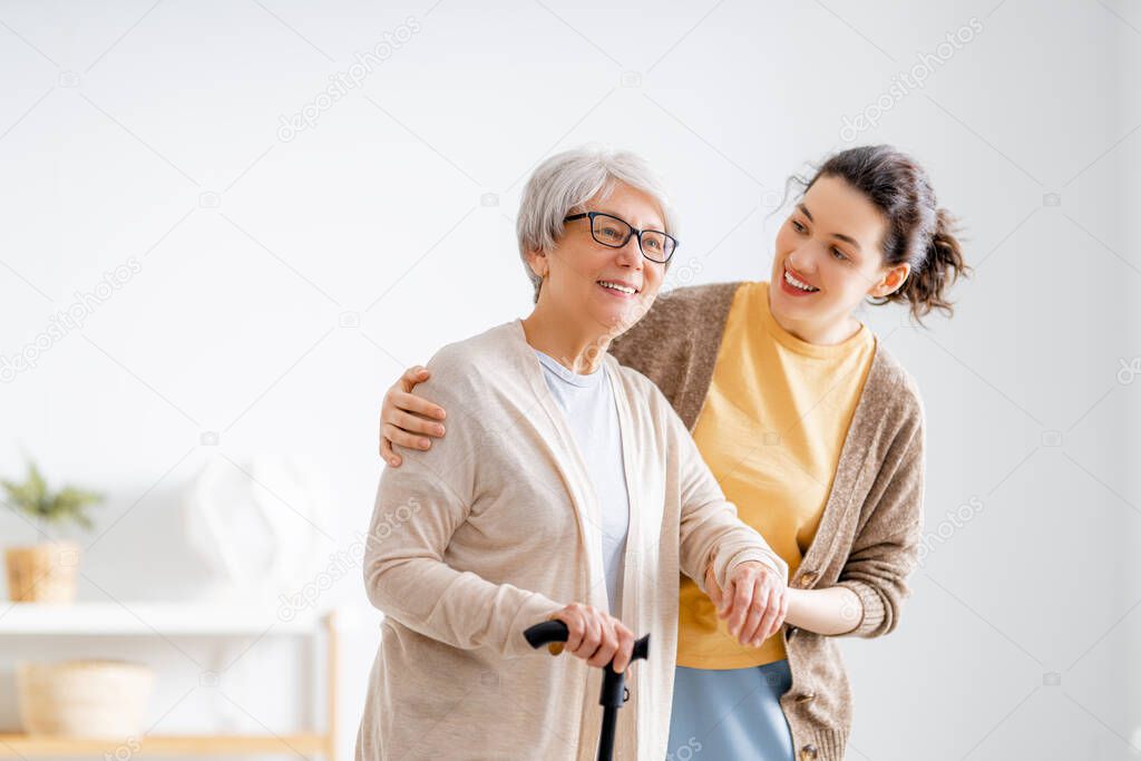 Happy patient and caregiver spending time together. Senior woman holding cane.