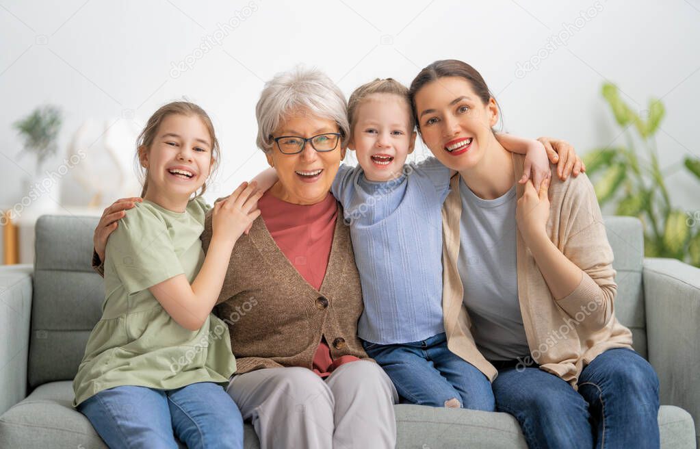 A nice girls, their mother and grandmother are hugging and  enjoying spending time together at home. 