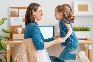 Bilgisayarda çalışan çocuklu genç bir anne. Aile evde. Uzak çalışma. 