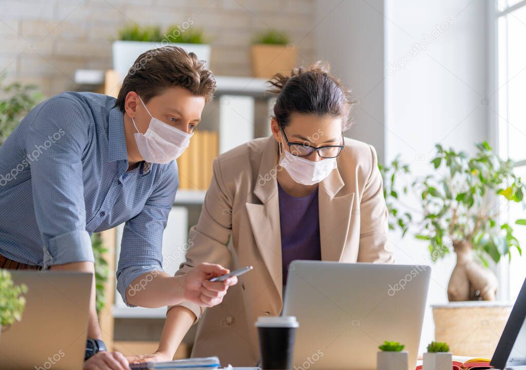 Businessman and businesswoman with medical mask working in office. Covid-19 time.