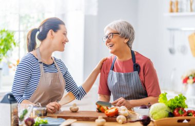Mutfakta mutlu bir aile. Anne ve yetişkin kızı düzgün bir yemek hazırlıyorlar.. 