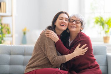 Güzel anne ve kız evdeki kanepede otururken konuşuyor ve gülümsüyor..