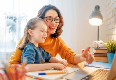 Bilgisayarda çalışan çocuklu genç bir anne. Aile evde. Uzak çalışma. 