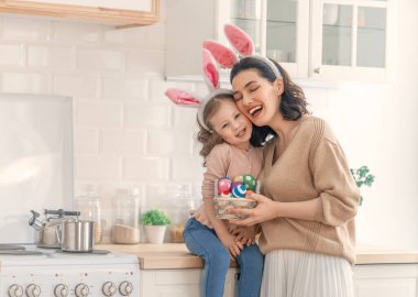 Mutlu aile birlikte fırın hazırlıyor. Anne ve kızı kurabiye pişiriyor ve mutfakta eğleniyorlar. Kız annesine bir buket çiçek veriyor..