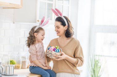 Mutlu aile birlikte fırın hazırlıyor. Anne ve kızı kurabiye pişiriyor ve mutfakta eğleniyorlar. Kız annesine bir buket çiçek veriyor..