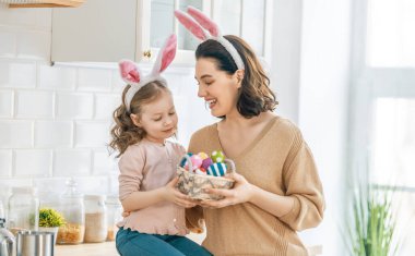 Mutlu aile birlikte fırın hazırlıyor. Anne ve kızı kurabiye pişiriyor ve mutfakta eğleniyorlar. Kız annesine bir buket çiçek veriyor..