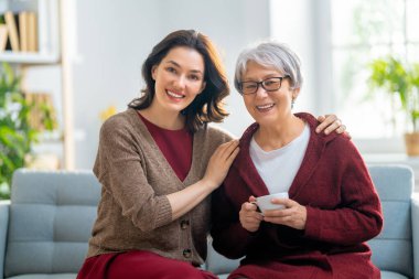 Güzel anne ve kız evdeki kanepede otururken konuşuyor ve gülümsüyor..