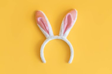 Mutlu Paskalyalar! Sarı arka planda tavşan kulakları.