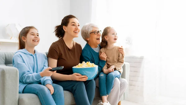 快乐的家庭看电视 家里放爆米花的电影 女儿和祖母在一起的时间 — 图库照片