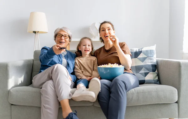 快乐的家庭看电视 家里放爆米花的电影 女儿和祖母在一起的时间 — 图库照片