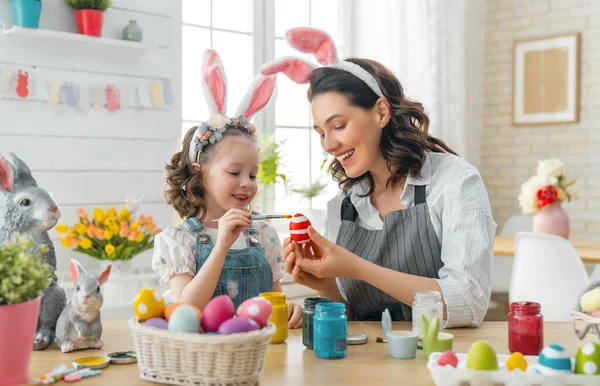 妈妈和她的女儿画鸡蛋 快乐的家庭为复活节做准备 可爱的小女孩 长着小兔子耳朵 — 图库照片