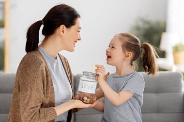 Anne ve kızı para kutusu tutuyor, kız para koyuyor. Para kutusu, para koyan kız.. 