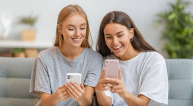 Genç kadınlar telefon kullanıyor. Komik kızlar evde eğleniyor..