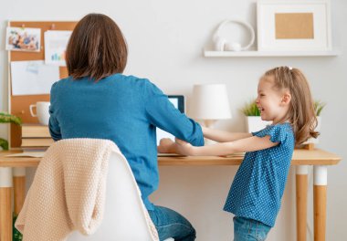 Bilgisayarda çalışan çocuklu genç bir anne. Aile evde. Uzak çalışma. 