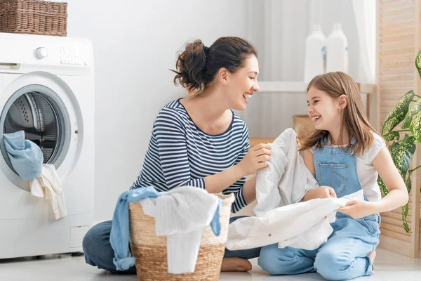 在家里洗衣服的时候 漂亮的年轻妇女和小女孩的小助手们都在开心地笑着 — 图库照片
