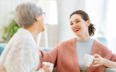 Güzel anne ve kız evdeki kanepede otururken konuşuyor ve gülümsüyor..