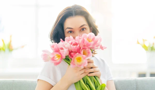 Piękna Młoda Kobieta Kwiatami Tulipany Rękach Siedzi Kanapie Domu — Zdjęcie stockowe