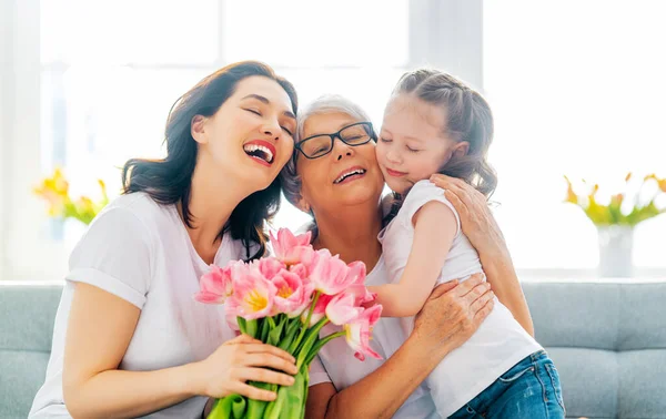 母亲节快乐 孩子的女儿在祝贺妈妈和奶奶送给他们的花郁金香 妈妈和女孩笑着和拥抱 家庭假日和团聚 — 图库照片