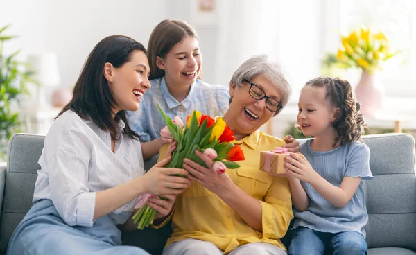 母亲节快乐 孩子的女儿和母亲都在祝贺奶奶送给她的花郁金香 妈妈和女孩们笑着拥抱 家庭假日和团聚 — 图库照片