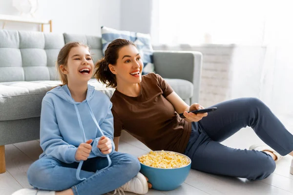快乐的家庭看电视 晚上在家里看爆米花电影 妈妈和女儿在一起 — 图库照片