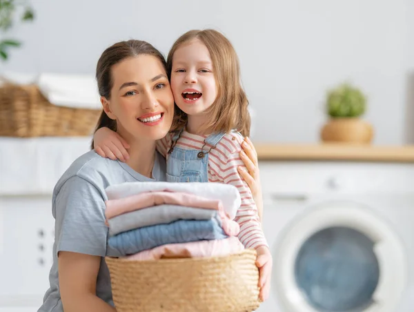 在家里洗衣服的时候 漂亮的年轻妇女和小女孩的小助手们都在开心地笑着 — 图库照片