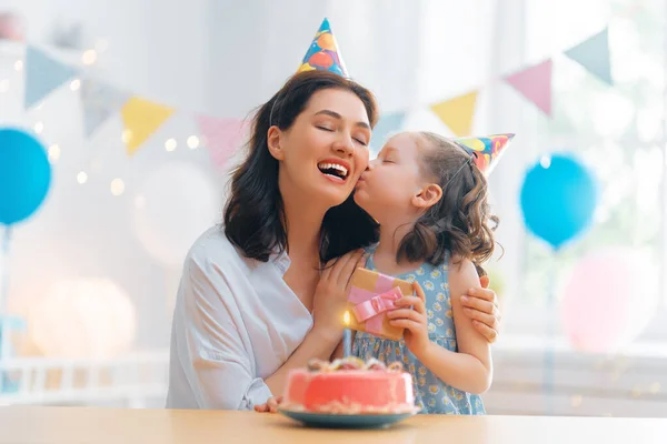 子供はケーキの上のろうそくを吹いている 母と娘は誕生日を祝っている — ストック写真