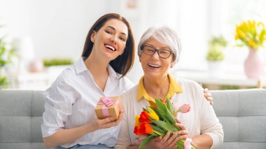 Güzel genç bir kadın ve elinde çiçeklerle annesi ellerinde laleler..