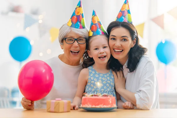 子供はケーキの上のろうそくを吹いている おばあちゃんとお母さんと娘さん — ストック写真