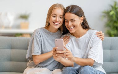 Genç kadınlar telefon kullanıyor. Komik kızlar evde eğleniyor..