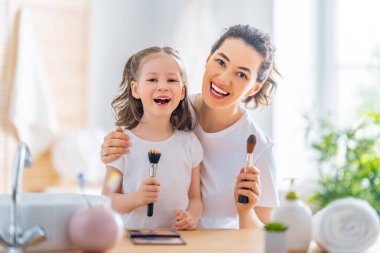 Sevgi dolu bir aile. Anne ve kızı makyaj yapıyor ve eğleniyorlar..