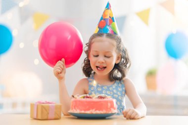 Çocuk pastanın üzerindeki mumları üflüyor. Çocuk doğum gününü kutluyor..