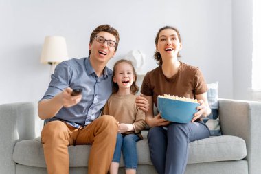 Evde patlamış mısırla televizyon izleyen mutlu bir aile. Anne, baba ve kızları birlikte vakit geçiriyorlar..