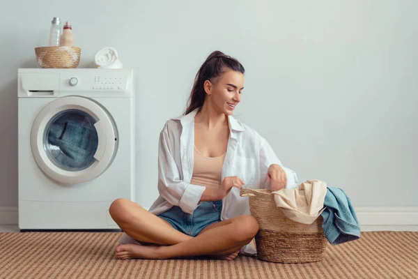 Hermosa Joven Mujer Sonríe Mientras Hace Colada Casa — Foto de Stock