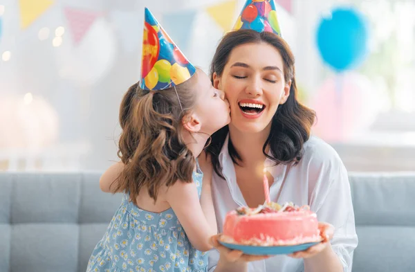 子供はケーキの上のろうそくを吹いている 母と娘は誕生日を祝っている — ストック写真
