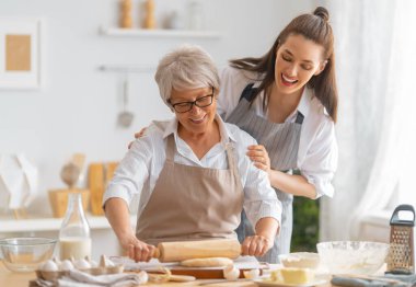 Mutfakta mutlu bir aile. Anne ve yetişkin kızı pasta hazırlıyorlar..