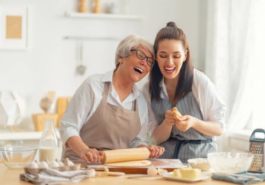 Mutfakta mutlu bir aile. Anne ve yetişkin kızı pasta hazırlıyorlar..