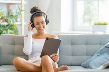 Genç kadın tablet kullanıyor. Komik kız evde kalıp eğleniyor..