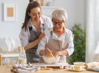 Mutfakta mutlu bir aile. Anne ve yetişkin kızı pasta hazırlıyorlar..