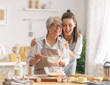 Mutfakta mutlu bir aile. Anne ve yetişkin kızı pasta hazırlıyorlar..