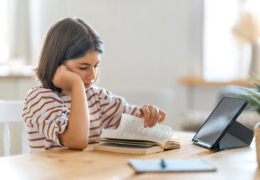 Okula dönelim. Mutsuz çocuk masada oturuyor. Ödev yapan ya da online eğitim alan kız.